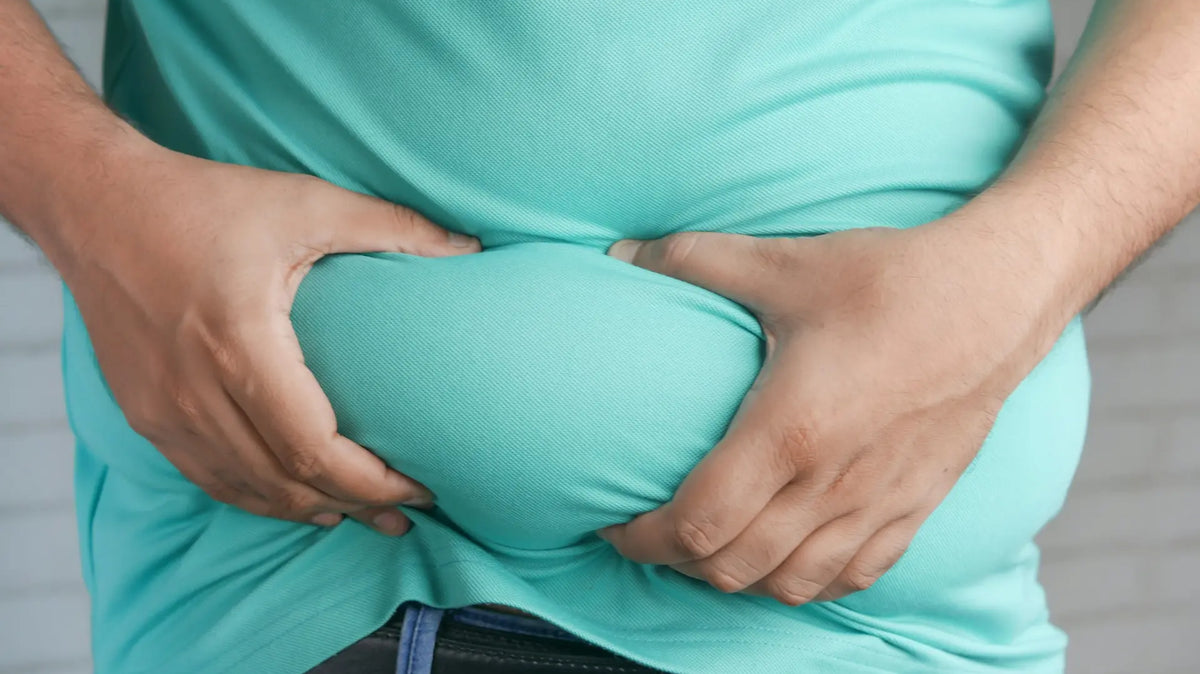 Man pinching belly fat, reflecting a symptom linked to high oestrogen levels — photo by Towfiqu Barbhuiya