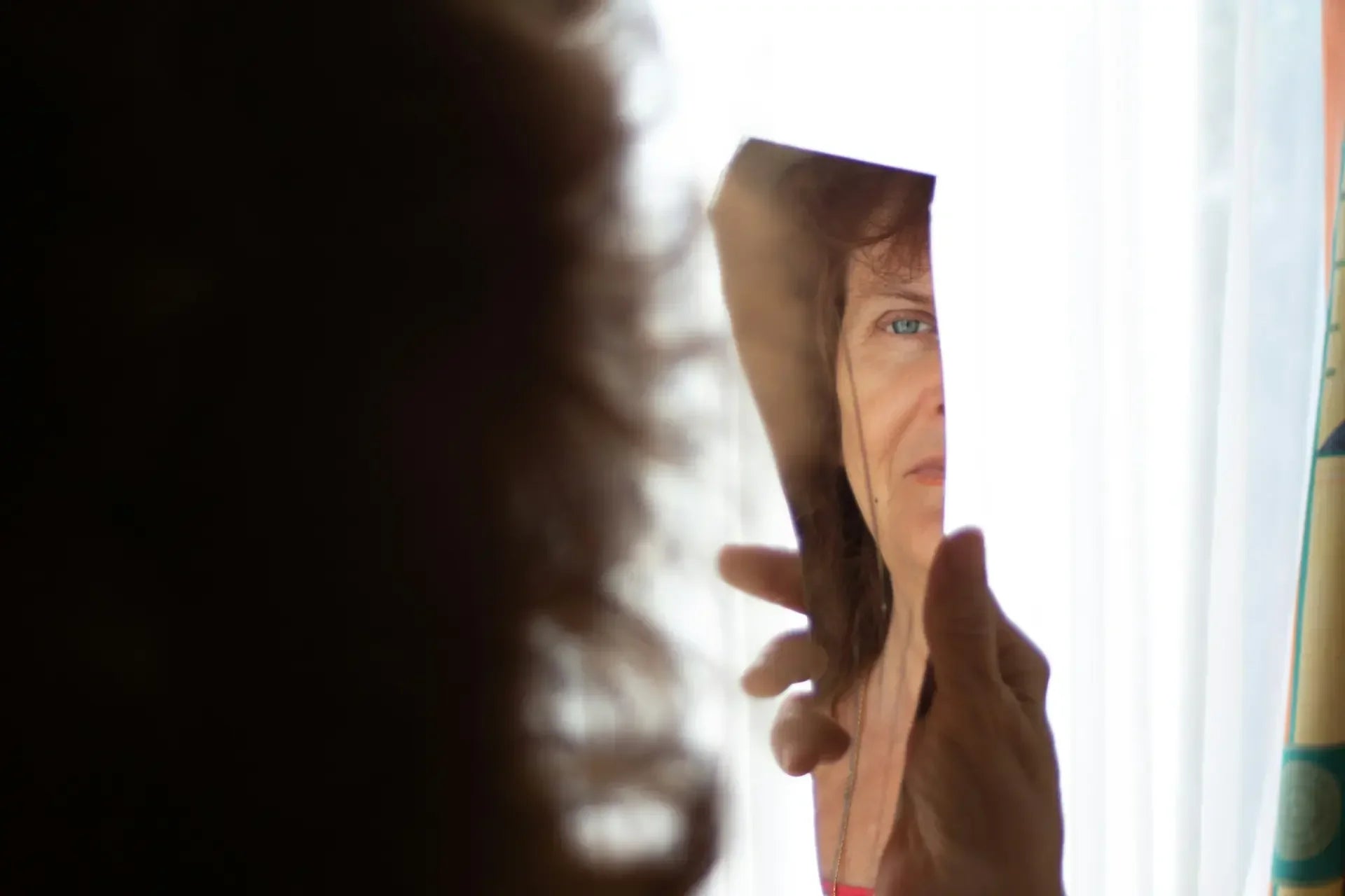 Woman looking at her reflection in a broken mirror, reflecting feelings of low self-esteem — photo by Anita Jankovic