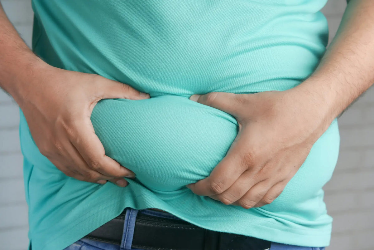 Man pinching belly fat, reflecting a symptom linked to high oestrogen levels — photo by Towfiqu Barbhuiya
